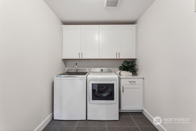 clothes washing area featuring cabinets, washing machine and dryer, and dark tile patterned floors