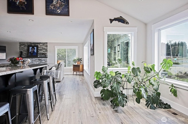 dining area with visible vents, lofted ceiling, baseboards, and light wood-style flooring