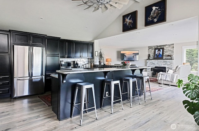 kitchen with a kitchen breakfast bar, light wood-style flooring, open floor plan, and appliances with stainless steel finishes