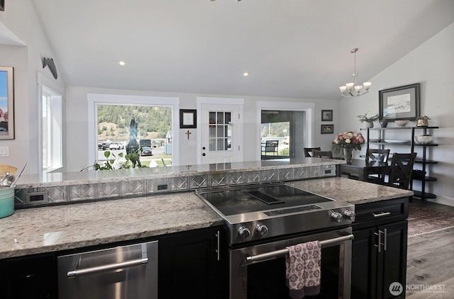 kitchen with a healthy amount of sunlight, an inviting chandelier, lofted ceiling, stainless steel range with electric cooktop, and dark cabinets