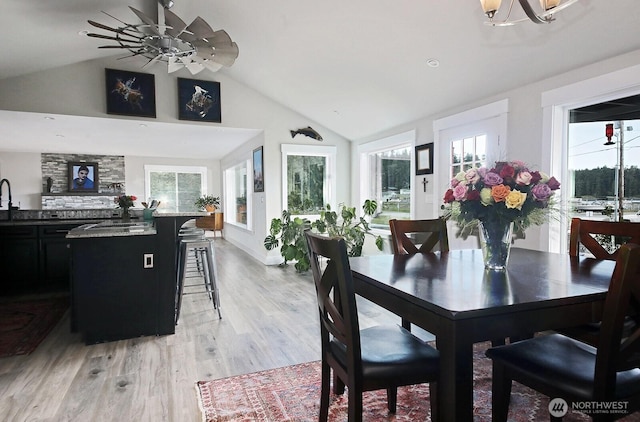 dining room with lofted ceiling, light wood-type flooring, and a chandelier