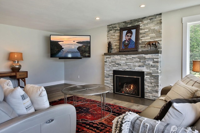 living area with a stone fireplace, recessed lighting, wood finished floors, and baseboards