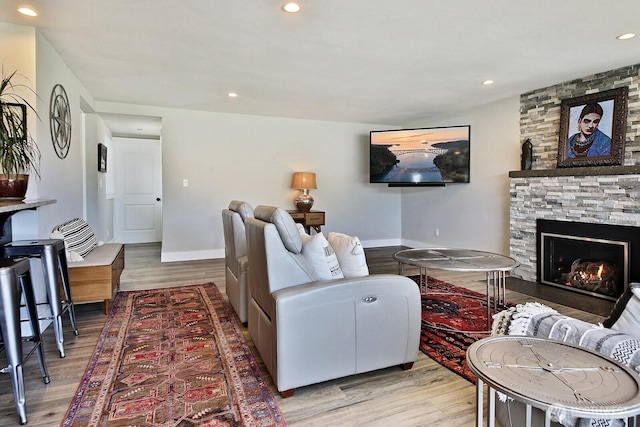 living area featuring recessed lighting, light wood-type flooring, baseboards, and a fireplace