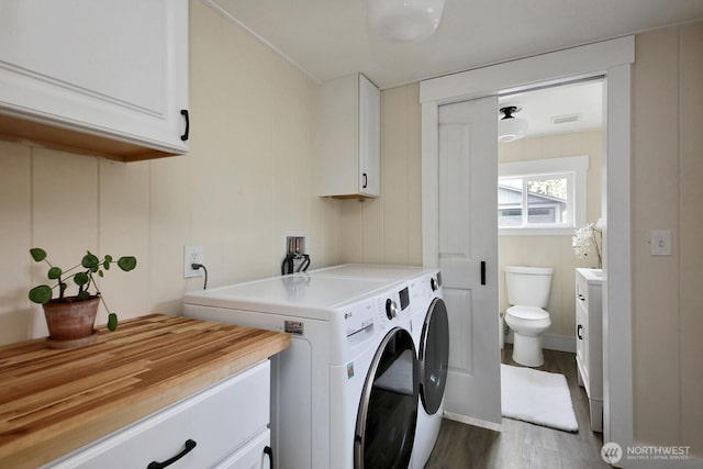 laundry area featuring cabinet space, dark wood-style floors, washing machine and dryer, and visible vents