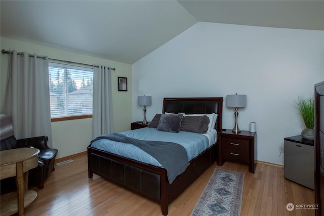 bedroom with vaulted ceiling and light hardwood / wood-style flooring