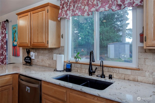 kitchen featuring light stone countertops, dishwasher, sink, and decorative backsplash