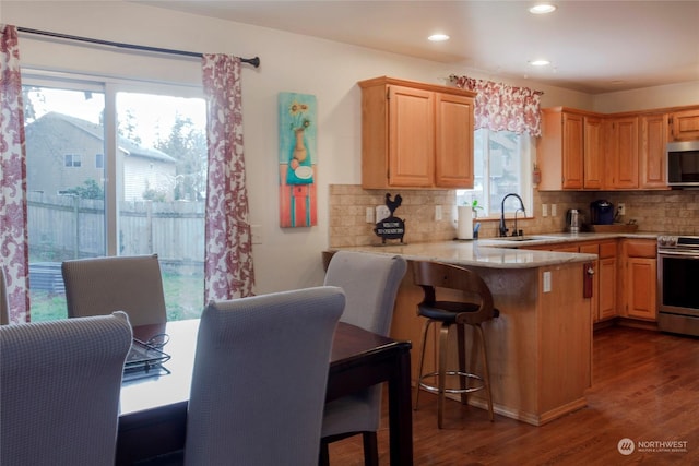 kitchen featuring sink, stainless steel appliances, dark hardwood / wood-style floors, decorative backsplash, and kitchen peninsula