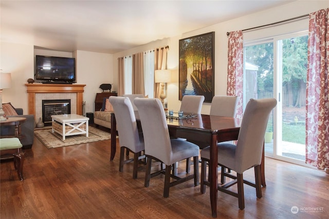 dining area with hardwood / wood-style flooring and a tiled fireplace