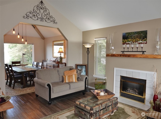 living room with hardwood / wood-style flooring, a tiled fireplace, and vaulted ceiling