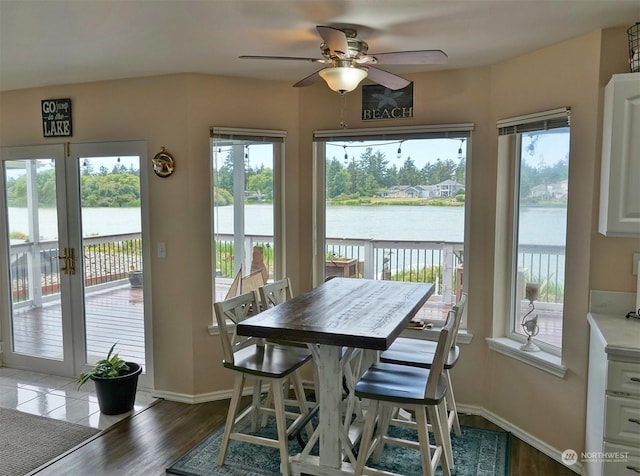 sunroom / solarium featuring a water view and ceiling fan