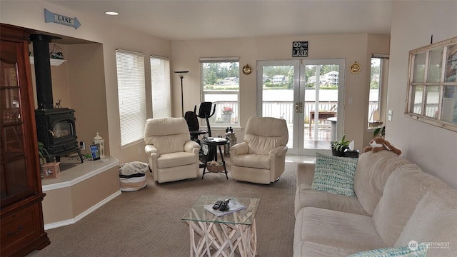 carpeted living room with french doors, plenty of natural light, and a wood stove