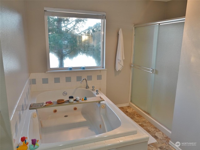 bathroom with tiled tub and a healthy amount of sunlight