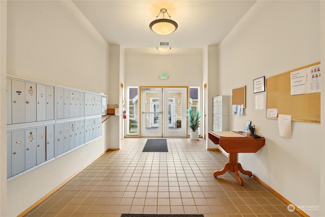 foyer with a towering ceiling, tile patterned floors, and mail boxes