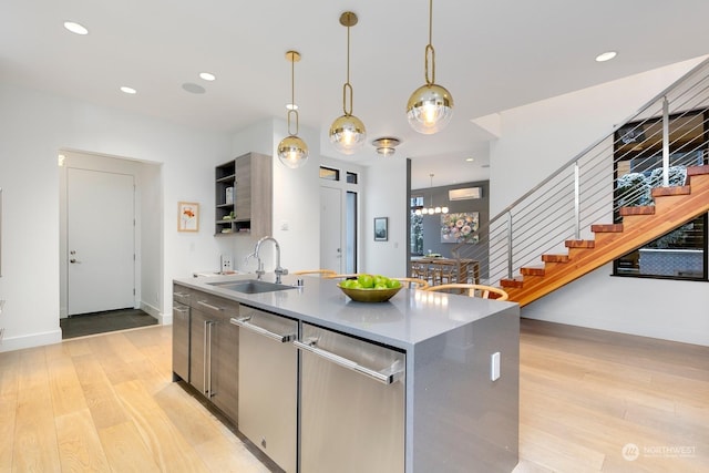 kitchen featuring pendant lighting, light hardwood / wood-style floors, sink, and dishwasher