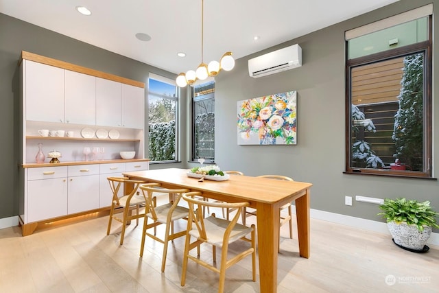 dining room with a wall unit AC and light hardwood / wood-style floors