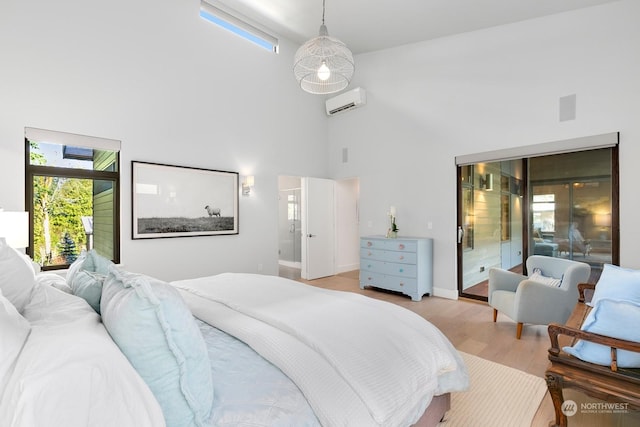 bedroom with light hardwood / wood-style floors, a wall unit AC, and a high ceiling