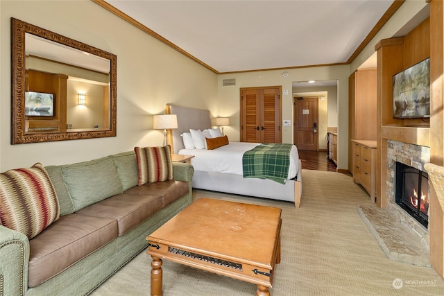 carpeted bedroom featuring a stone fireplace and ornamental molding