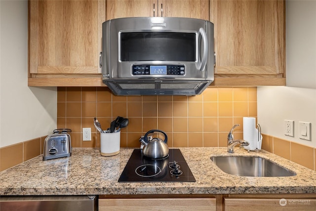 kitchen featuring sink, black electric stovetop, light stone counters, and decorative backsplash