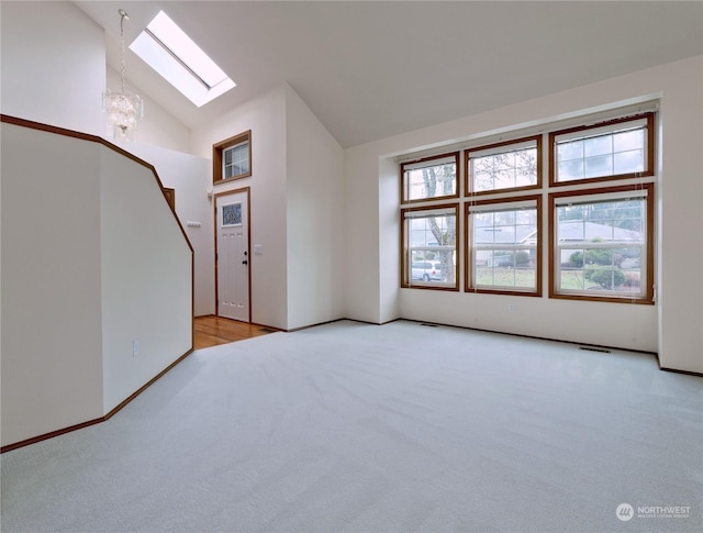 bonus room featuring light carpet, a skylight, high vaulted ceiling, and an inviting chandelier