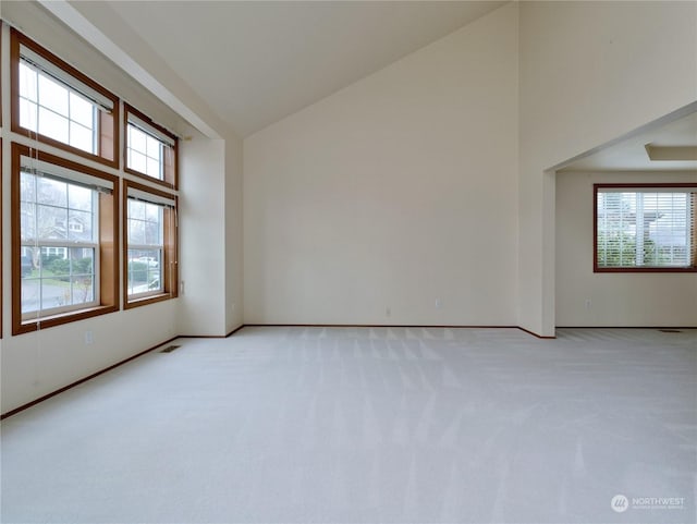 carpeted empty room with high vaulted ceiling