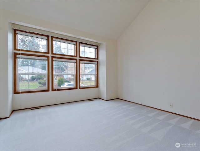 empty room with light carpet, plenty of natural light, and high vaulted ceiling