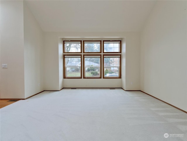 carpeted spare room featuring vaulted ceiling and a healthy amount of sunlight