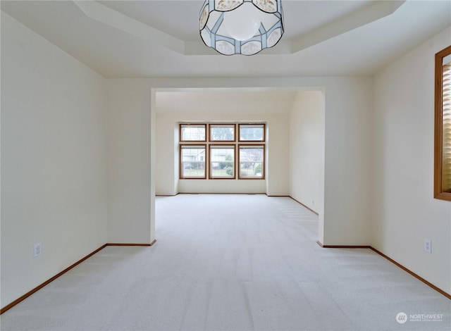 carpeted empty room featuring a raised ceiling