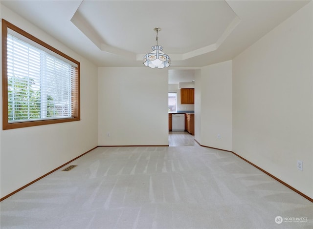 unfurnished room featuring light carpet and a tray ceiling