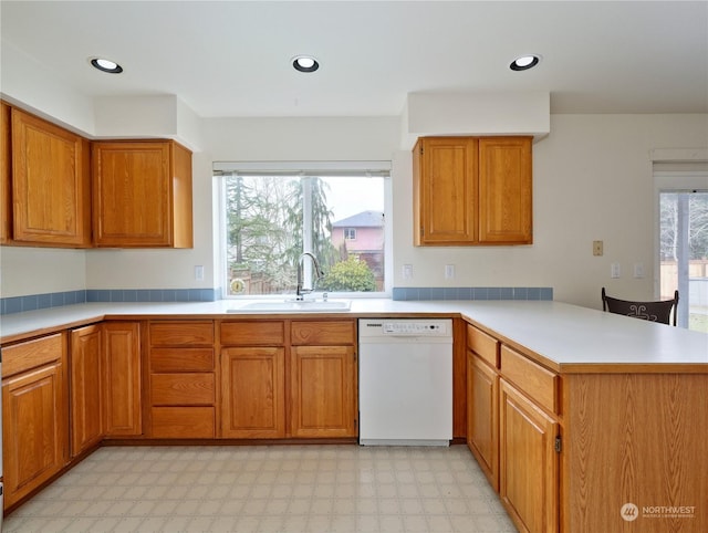 kitchen with a healthy amount of sunlight, white dishwasher, kitchen peninsula, and sink