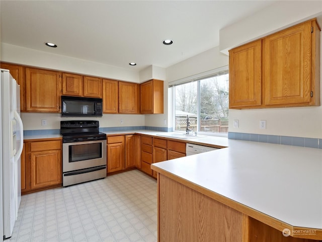 kitchen featuring stainless steel electric range oven, white refrigerator with ice dispenser, sink, and kitchen peninsula