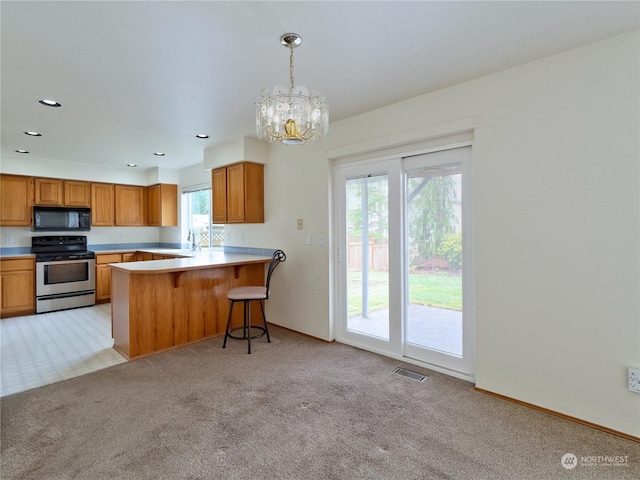 kitchen with decorative light fixtures, light carpet, electric range, a kitchen breakfast bar, and kitchen peninsula