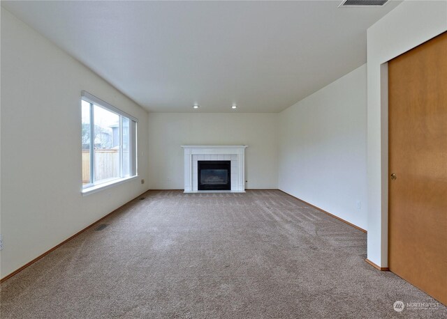 unfurnished living room with light carpet and a fireplace