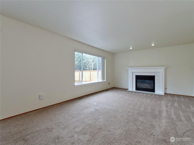 unfurnished living room with a tiled fireplace and light carpet