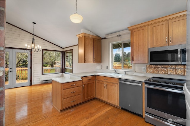 kitchen with lofted ceiling, sink, decorative light fixtures, appliances with stainless steel finishes, and light hardwood / wood-style floors