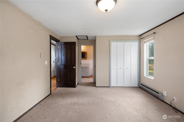 unfurnished bedroom with a baseboard radiator, ensuite bath, a closet, and light carpet