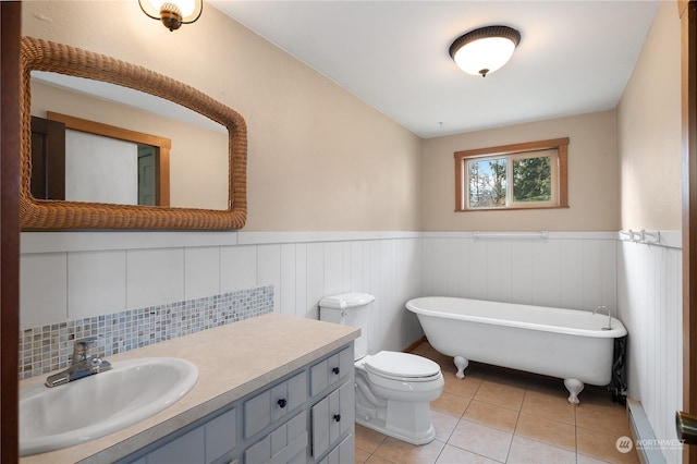 bathroom featuring tile patterned flooring, vanity, a tub, and toilet