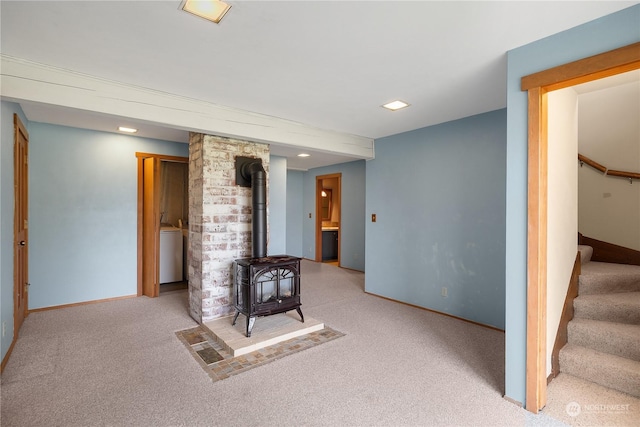 unfurnished living room with light colored carpet and a wood stove