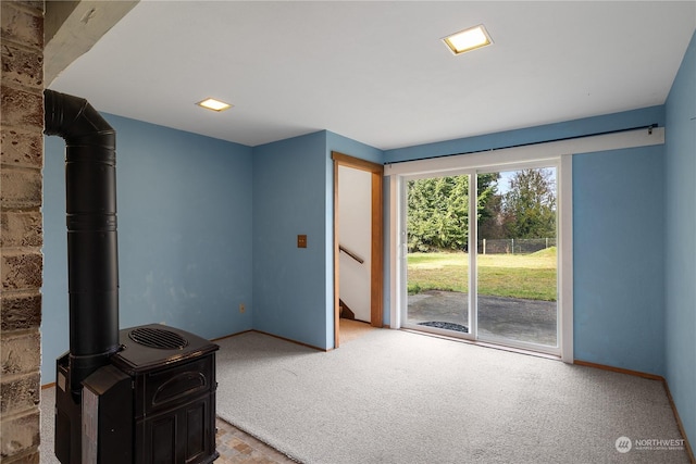 unfurnished living room with light colored carpet and a wood stove