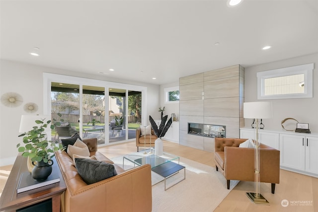 living room featuring a tiled fireplace and light wood-type flooring