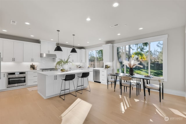 kitchen with decorative light fixtures, white cabinets, and appliances with stainless steel finishes