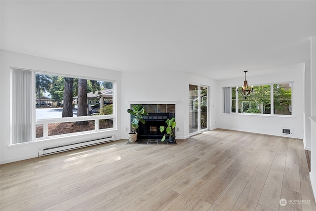 unfurnished living room with a notable chandelier, light wood-type flooring, a tile fireplace, and a baseboard heating unit