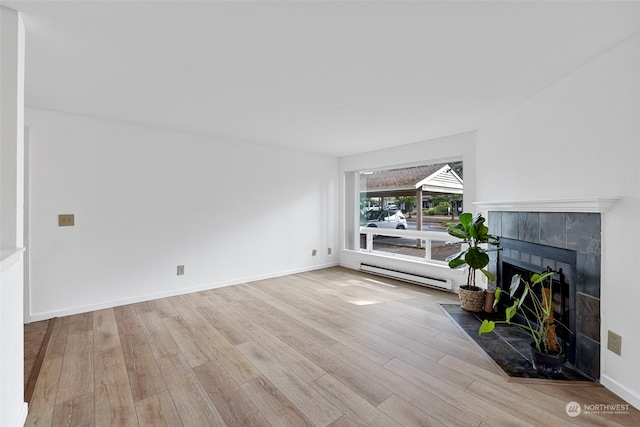 living room featuring baseboard heating, a fireplace, and light hardwood / wood-style floors