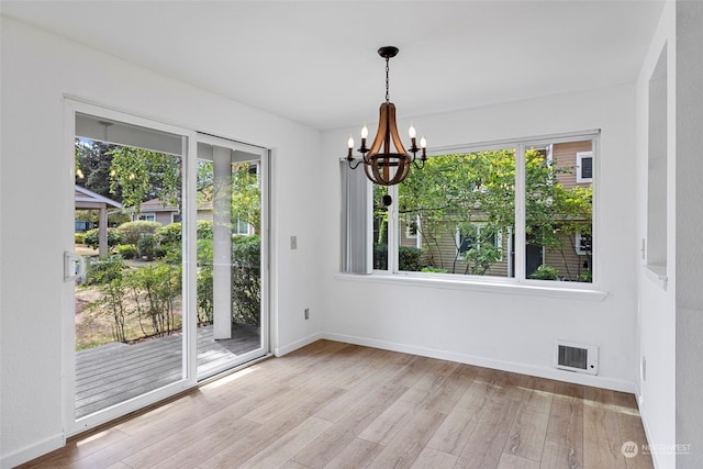 unfurnished dining area featuring light hardwood / wood-style flooring and a notable chandelier