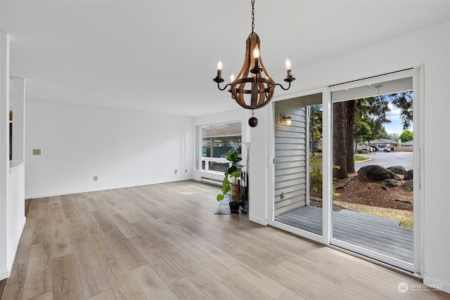 unfurnished room featuring a notable chandelier and light hardwood / wood-style floors