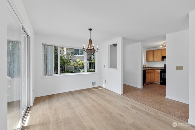 unfurnished dining area with an inviting chandelier and light wood-type flooring