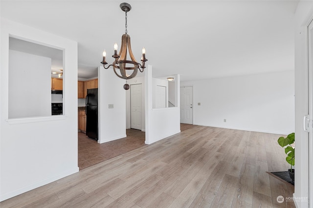 unfurnished dining area featuring a chandelier and light hardwood / wood-style floors