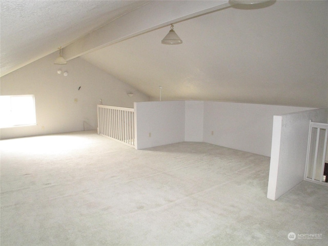 bonus room featuring lofted ceiling with beams, light carpet, and a textured ceiling