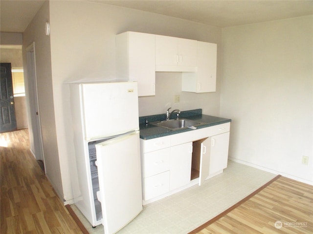 kitchen with white refrigerator, sink, light hardwood / wood-style flooring, and white cabinets