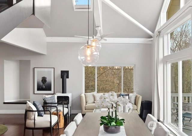 dining space featuring hardwood / wood-style floors, a towering ceiling, a skylight, and a wood stove