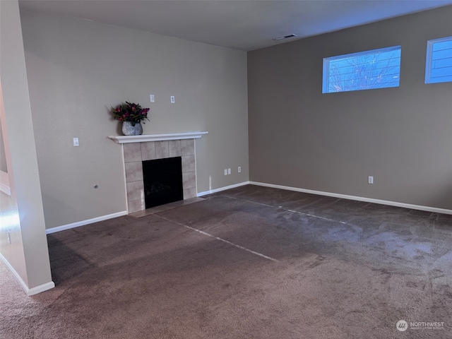 unfurnished living room featuring dark carpet and a tile fireplace